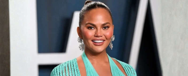 Chrissy Teigen sorrindo em evento de gala