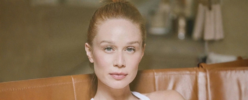 Mulher com cabelo preso, sentada em sofá de couro