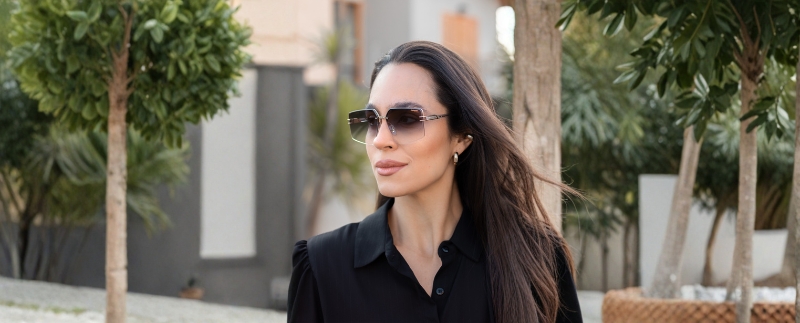 Mulher elegante com óculos escuros em ambiente urbano.