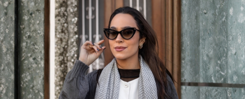 Mulher com óculos escuros e cachecol estiloso.