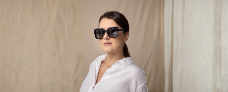 Mulher com óculos escuros em fundo neutro